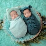 Dwa noworodki spokojnie śpiące w miękkich otulaczach na puchatym kocu