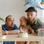 Dwóch ojców świętuje urodziny niemowlaka z tortem i prezentami