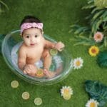 Niemowlę siedzące w wanience z cytrusami na tle zieleni