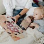 Rodzic czyta książkę małemu dziecku tulącemu pluszową sowę