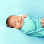 Śpiący noworodek otulony miękkim kocykiem