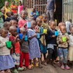 Afrykańskie dzieci z kolorowymi kubkami na dworze w słoneczny dzień