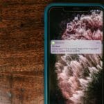 Smartfon na drewnianym blacie z komunikatem o wykrytym oszustwie