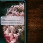 Smartfon z powiadomieniem o alercie bankowym na drewnianym stole