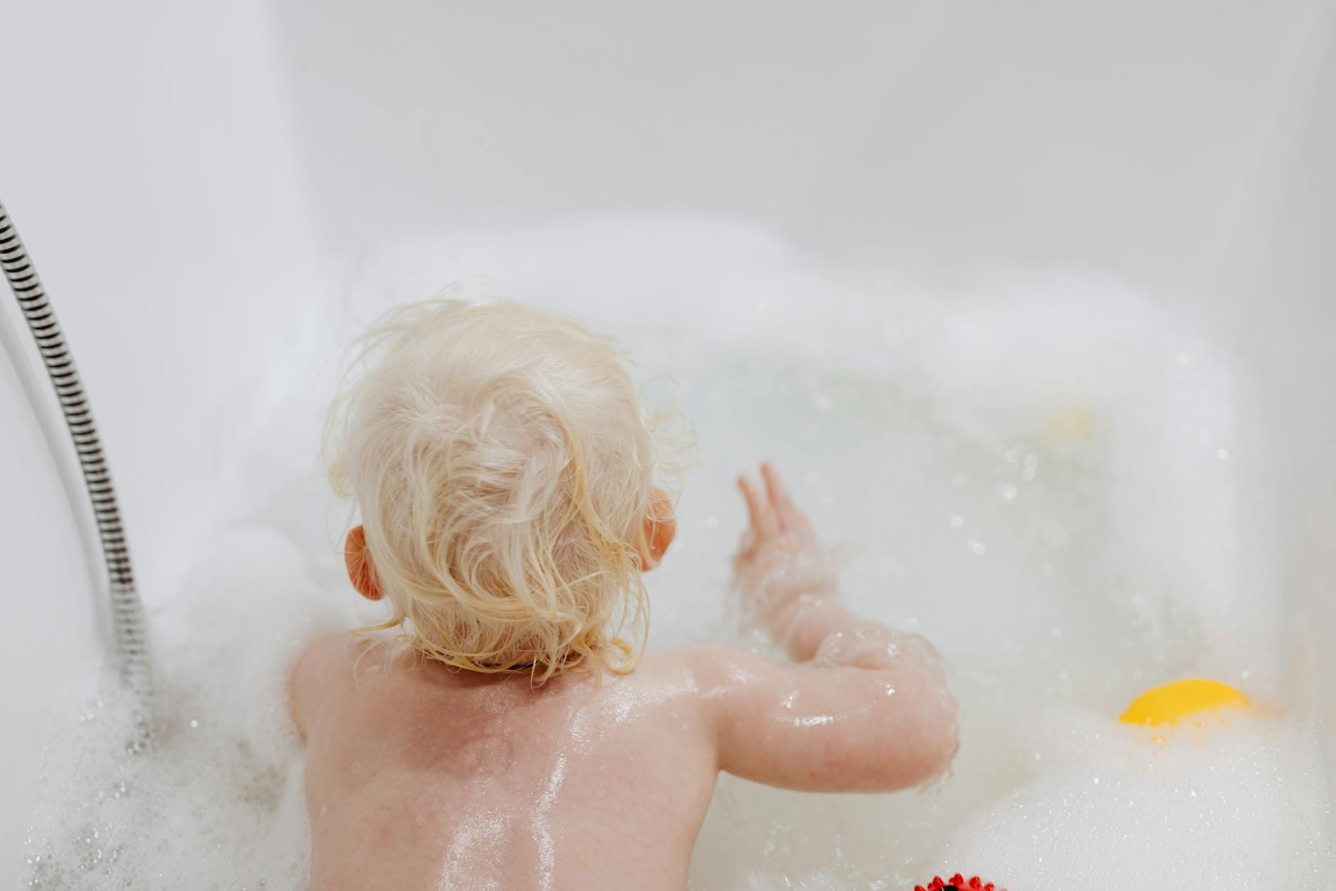 Małe dziecko bawi się w wannie pełnej piany podczas wieczornej kąpieli
