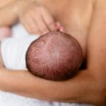 Mama karmiąca piersią noworodka na rękach
