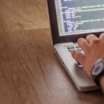 Programista piszący kod Java na laptopie z testami jednostkowymi