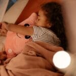 Śpiąca dziewczynka tuli różowego pluszaka w przytulnym łóżku