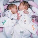 Śpiące bliźnięta w piżamkach przytulone do pluszowych zabawek