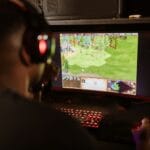Gracz przy biurku wpatrzony w monitor z grą survival na PC