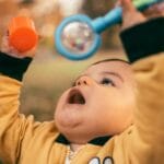 Niemowlę bawi się kolorową zabawką na dworze w jesienny dzień