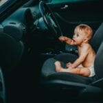 Niemowlę siedzące na fotelu kierowcy w samochodzie podczas podróży