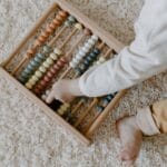 Niemowlę bawi się kolorowym drewnianym liczydłem Montessori