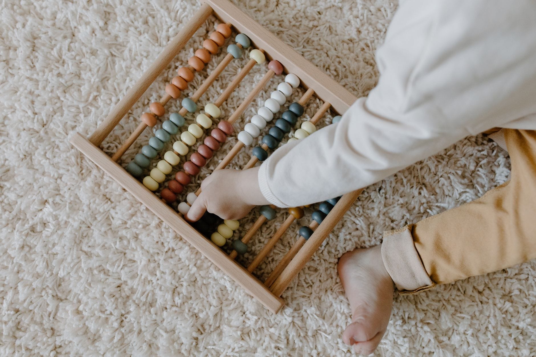 Niemowlę bawi się kolorowym drewnianym liczydłem Montessori